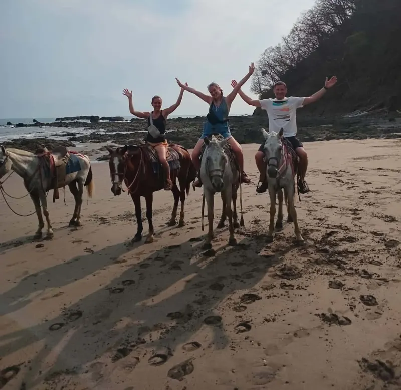 Group horseback riding along the sand on Jacó Beach