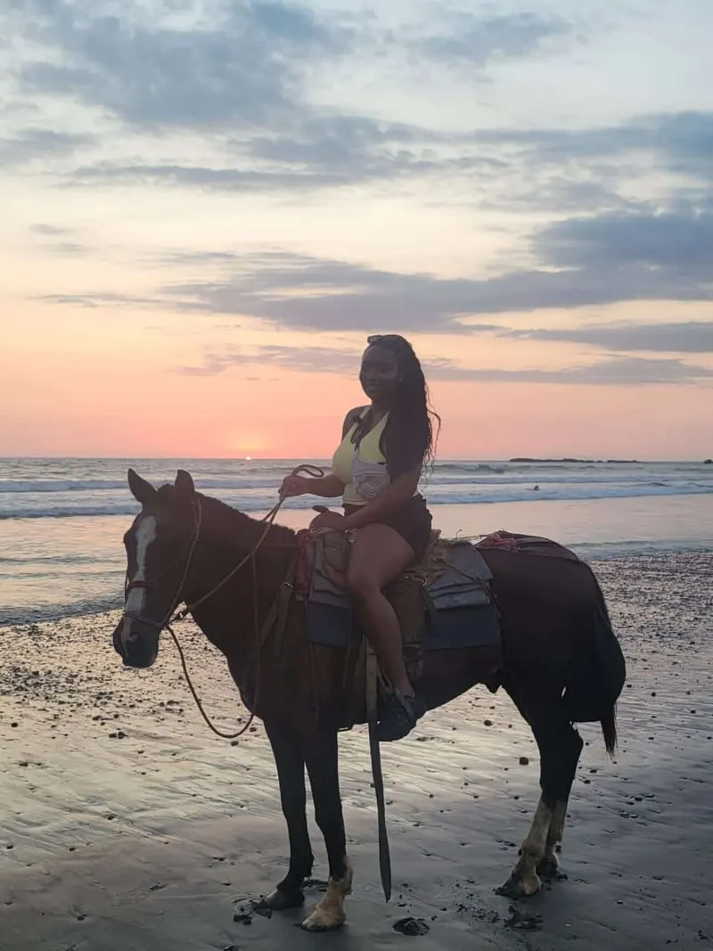 A woman enjoying a horse riding experience at sunset on Jacó Beach, Costa Rica