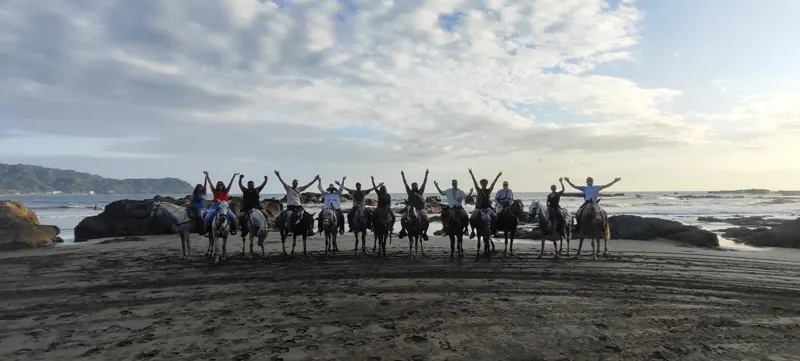 A large group horseback riding along Jacó Beach in Costa Rica